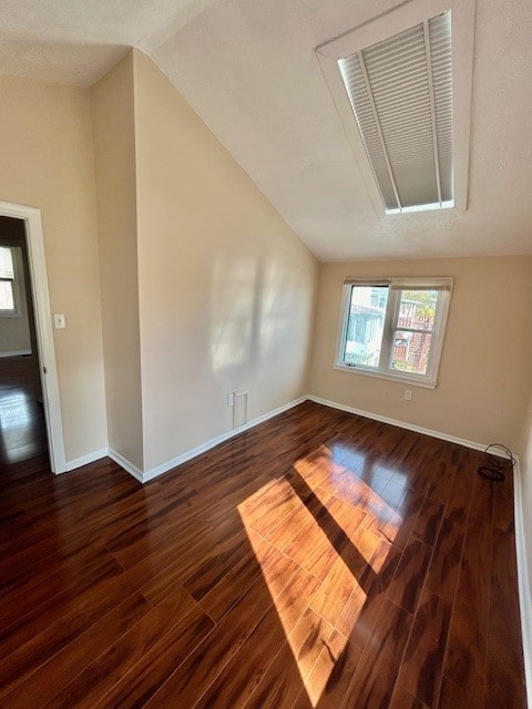 spare room featuring dark wood-type flooring and vaulted ceiling