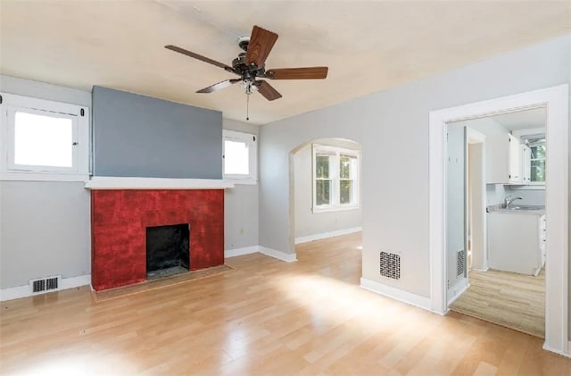 unfurnished living room with sink, light hardwood / wood-style flooring, and ceiling fan