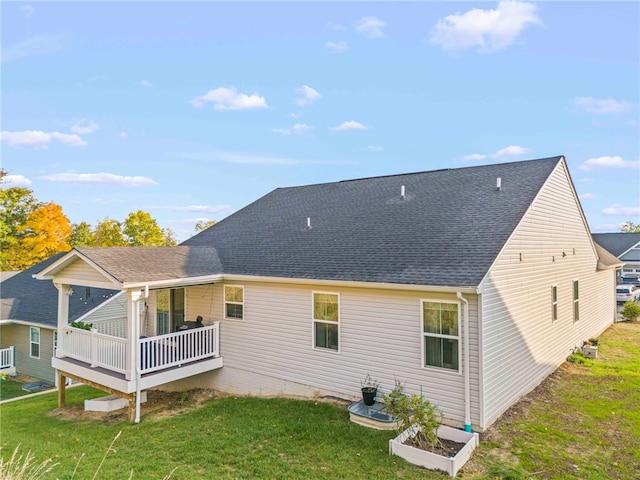 rear view of house with roof with shingles, a wooden deck, and a yard