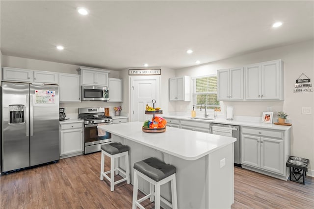 kitchen featuring sink, a center island, a kitchen bar, appliances with stainless steel finishes, and light hardwood / wood-style floors