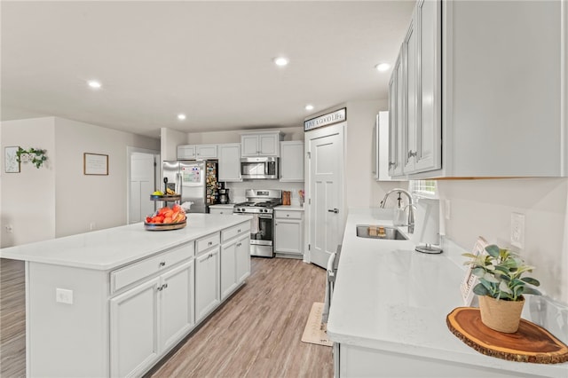 kitchen featuring a kitchen island, light hardwood / wood-style flooring, stainless steel appliances, sink, and white cabinetry