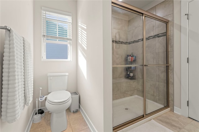 bathroom featuring a stall shower, baseboards, tile patterned flooring, and toilet