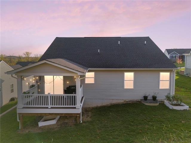 back house at dusk featuring a wooden deck and a yard