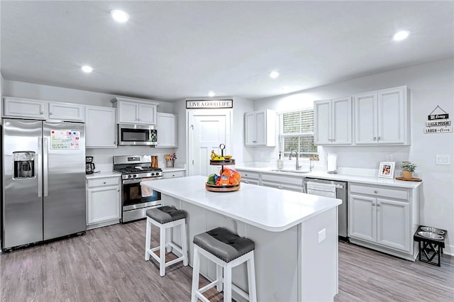 kitchen with a center island, a breakfast bar area, appliances with stainless steel finishes, a sink, and light wood-type flooring