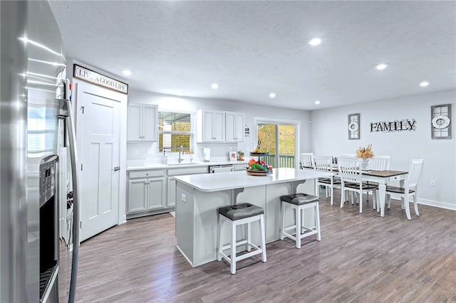 kitchen featuring a breakfast bar area, wood finished floors, light countertops, stainless steel appliances, and a sink