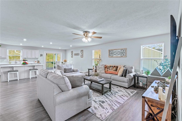 living area with recessed lighting, dark wood-style flooring, ceiling fan, and a textured ceiling