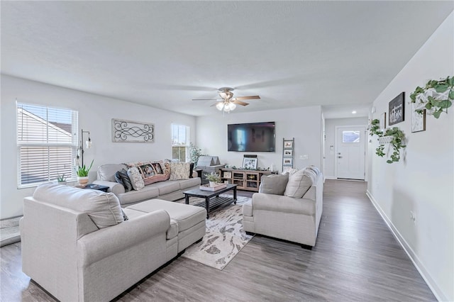 living area featuring wood finished floors, a ceiling fan, and baseboards