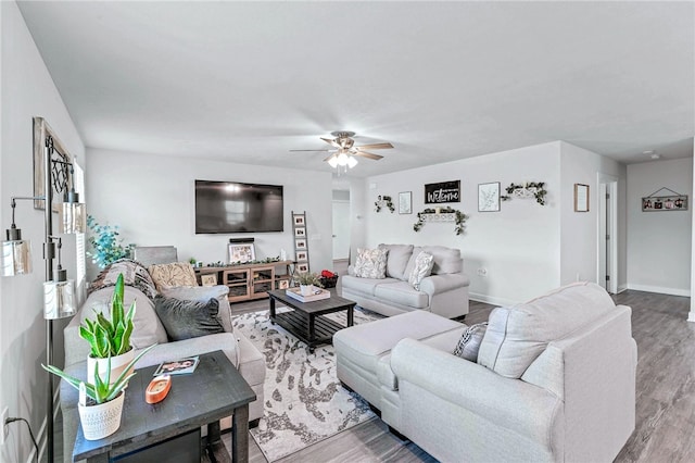 living area with a ceiling fan, baseboards, and wood finished floors