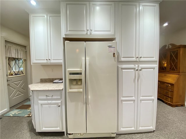 kitchen with light carpet, white fridge with ice dispenser, and white cabinets