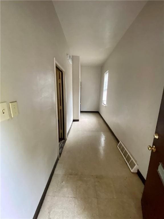 hallway featuring baseboards and concrete flooring