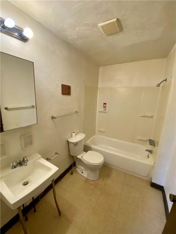 full bath featuring a sink, shower / washtub combination, toilet, and tile patterned flooring