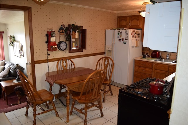 dining space featuring light tile patterned flooring, crown molding, and sink