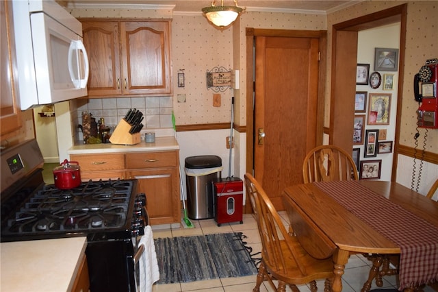 kitchen with black gas stove, crown molding, and light tile patterned floors