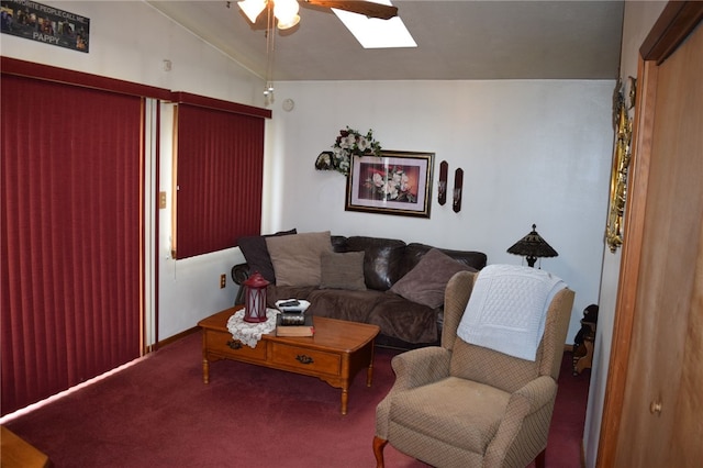 carpeted living room with ceiling fan and lofted ceiling with skylight