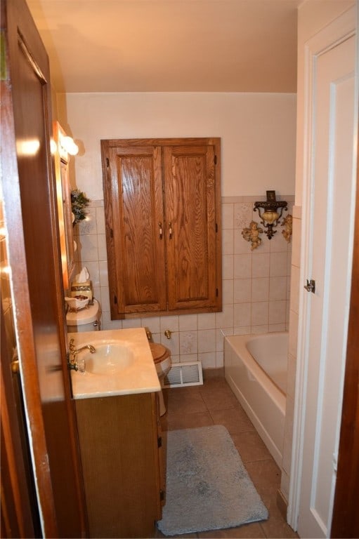 bathroom featuring a washtub, toilet, vanity, and tile walls