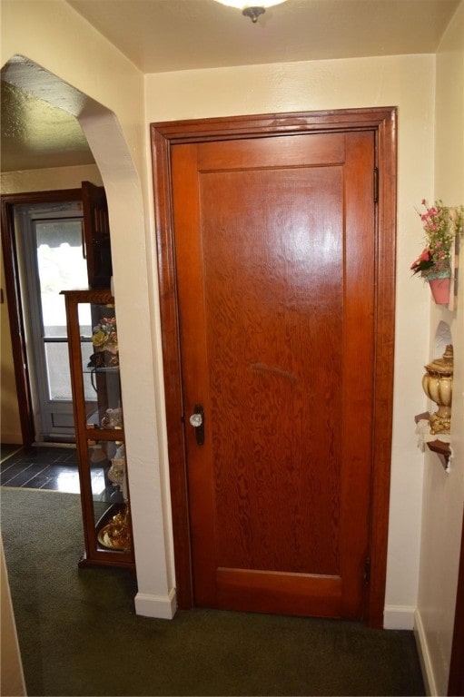 hall with dark colored carpet