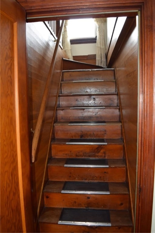 staircase featuring wooden walls