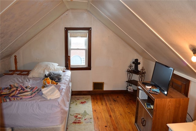 bedroom with hardwood / wood-style floors and vaulted ceiling