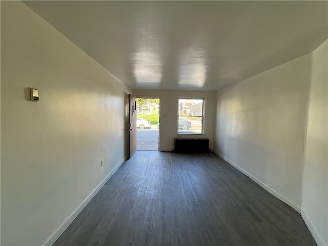 unfurnished room featuring radiator heating unit and dark hardwood / wood-style floors