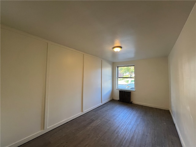 spare room with dark hardwood / wood-style floors and radiator