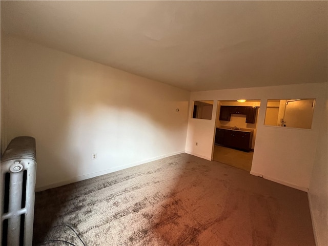 unfurnished living room with dark carpet, lofted ceiling, and radiator heating unit