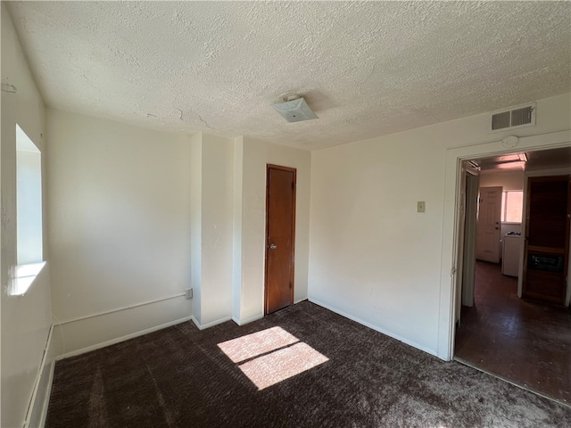 carpeted empty room with a textured ceiling