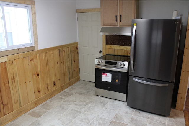 kitchen featuring stainless steel appliances and wood walls