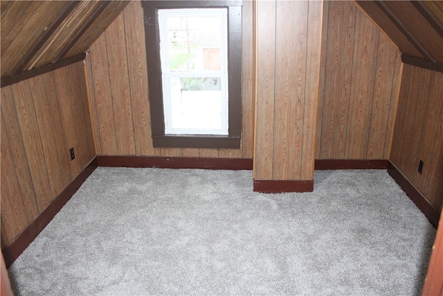 additional living space featuring wooden walls, vaulted ceiling, and light colored carpet