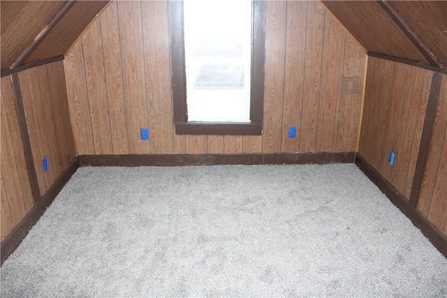 bonus room featuring light colored carpet, wood walls, and vaulted ceiling