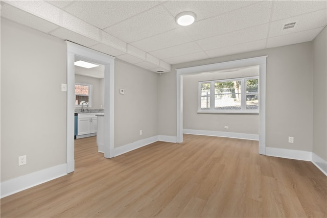 unfurnished room featuring a drop ceiling, light wood-type flooring, and sink