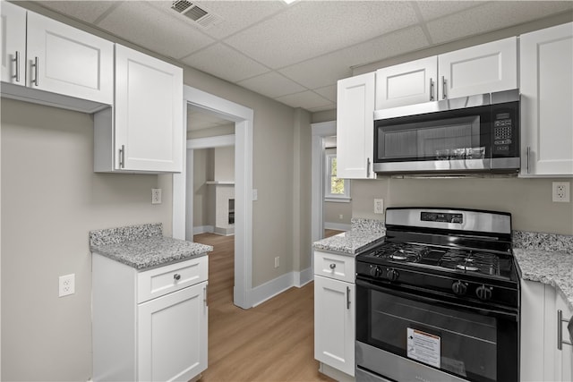 kitchen featuring a drop ceiling, stainless steel appliances, and white cabinets