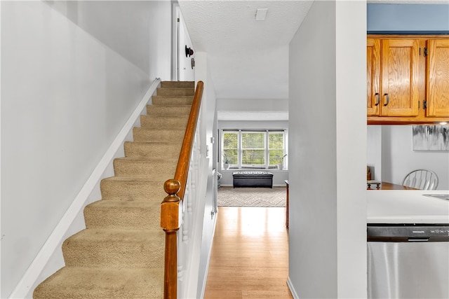 stairway with hardwood / wood-style flooring and a textured ceiling