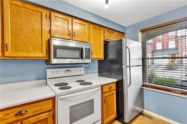 kitchen featuring light hardwood / wood-style floors, stainless steel appliances, and a textured ceiling