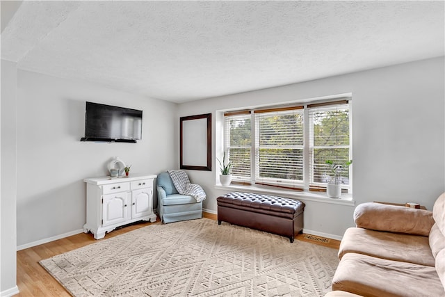 living room featuring light wood-type flooring and a textured ceiling