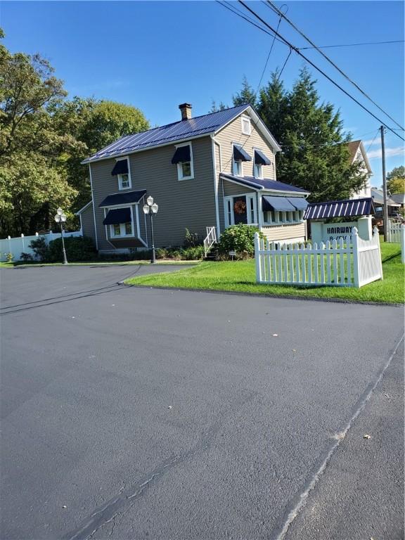 view of home's exterior featuring metal roof, a chimney, and a fenced front yard