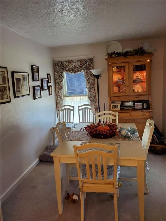 dining space featuring light carpet, a textured ceiling, and baseboards