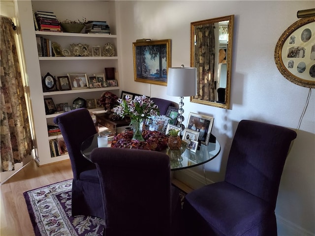 dining space featuring built in shelves and hardwood / wood-style flooring