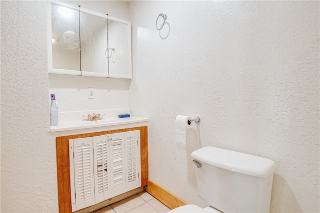 bathroom with toilet, vanity, and tile patterned floors