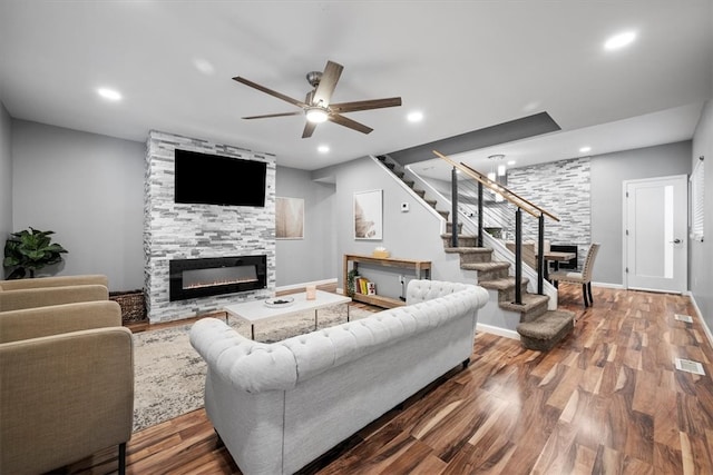 living room with a fireplace, ceiling fan, and wood-type flooring