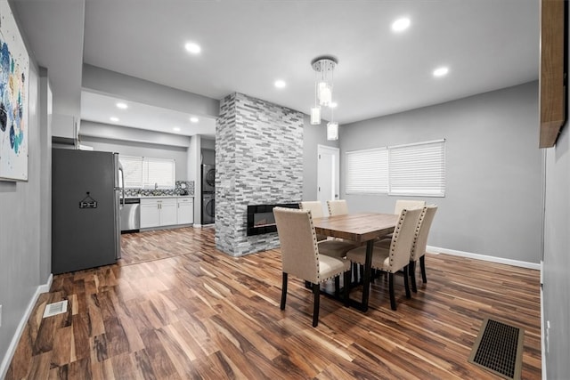 dining room with a stone fireplace and hardwood / wood-style floors