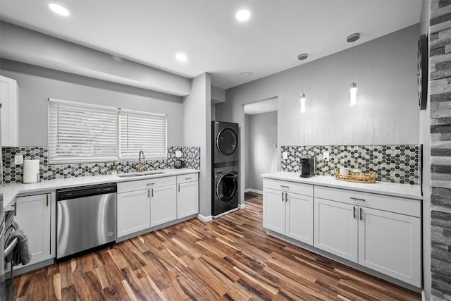 kitchen with stacked washer and clothes dryer, stainless steel appliances, hanging light fixtures, and white cabinetry