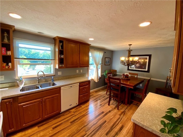 kitchen with decorative light fixtures, a textured ceiling, white dishwasher, sink, and hardwood / wood-style floors