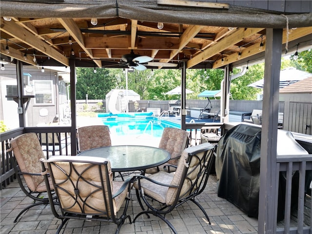 view of patio with a fenced in pool, ceiling fan, and a storage shed