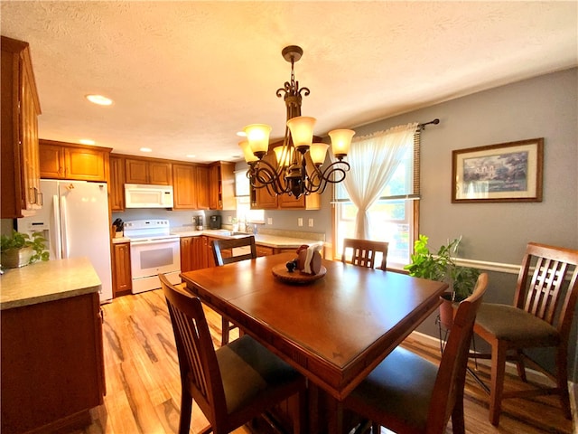 dining area with a textured ceiling, light hardwood / wood-style floors, a chandelier, and sink