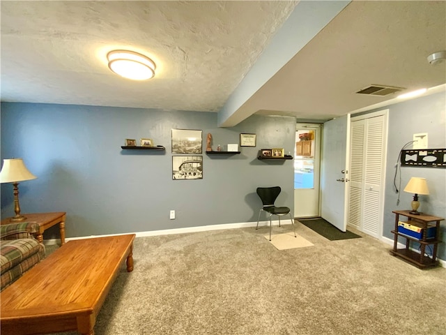 sitting room with a textured ceiling and carpet flooring