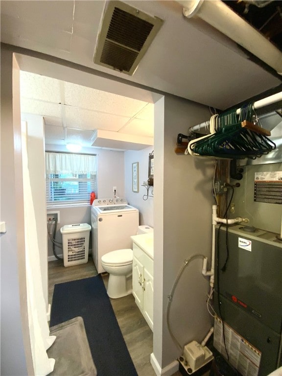 bathroom with hardwood / wood-style floors, washer / dryer, and heating unit