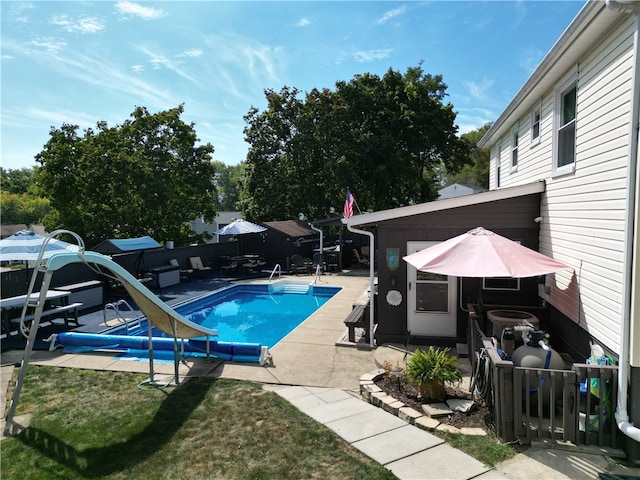 view of swimming pool with a patio, a yard, and a water slide