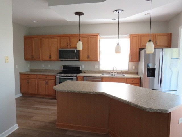 kitchen with hanging light fixtures, sink, a kitchen island, appliances with stainless steel finishes, and dark hardwood / wood-style floors