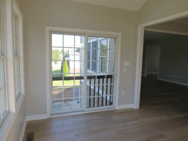 doorway with lofted ceiling and light hardwood / wood-style floors