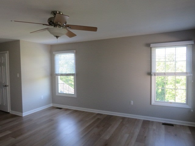 unfurnished room featuring ceiling fan, dark hardwood / wood-style flooring, and a wealth of natural light